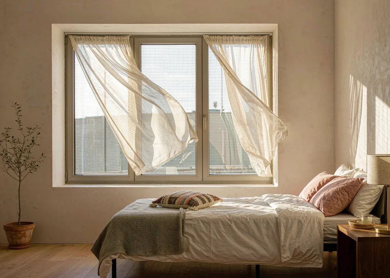 Bedroom with slim bronze aluminum casement window and sheer curtains