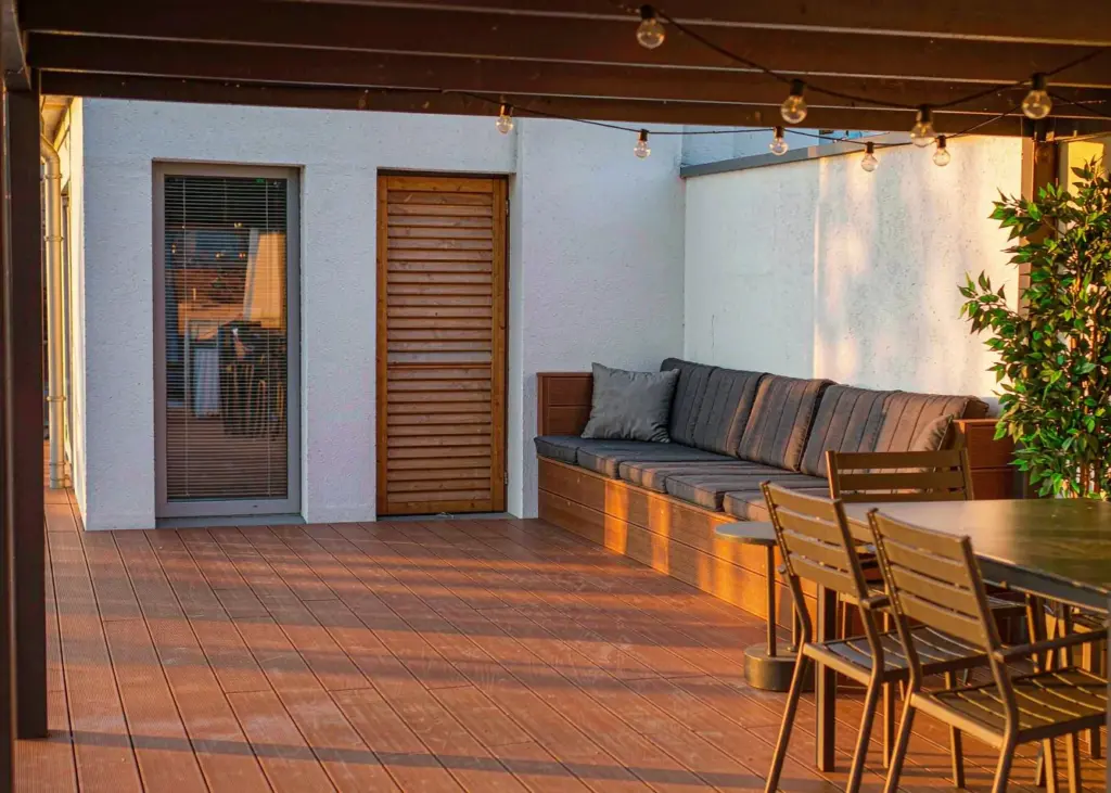 Modern backyard composite deck in walnut tone with dining set and string lights
