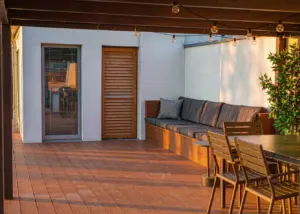 Modern backyard composite deck in walnut tone with dining set and string lights
