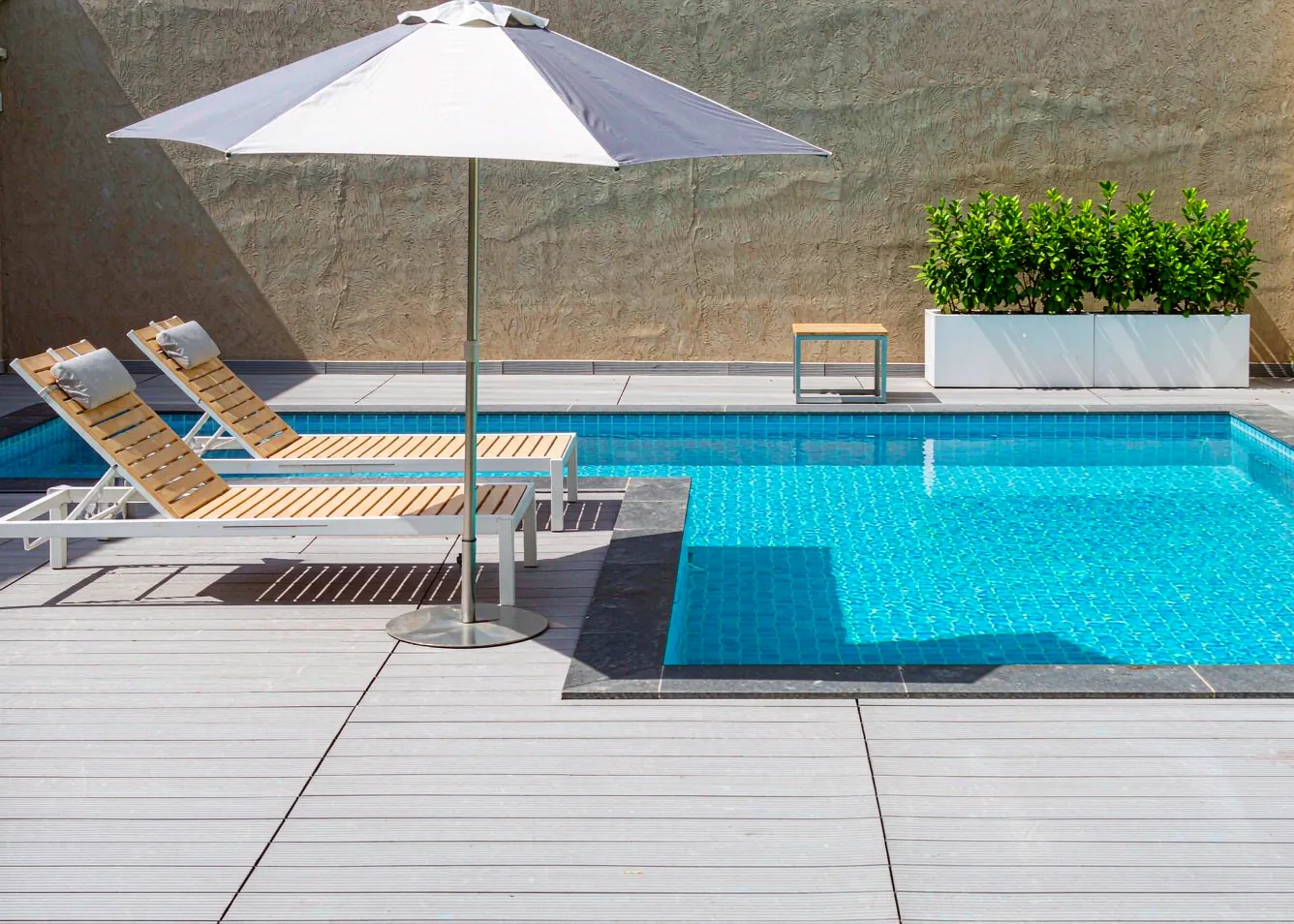 Light grey composite pool deck with loungers in minimalist resort style
