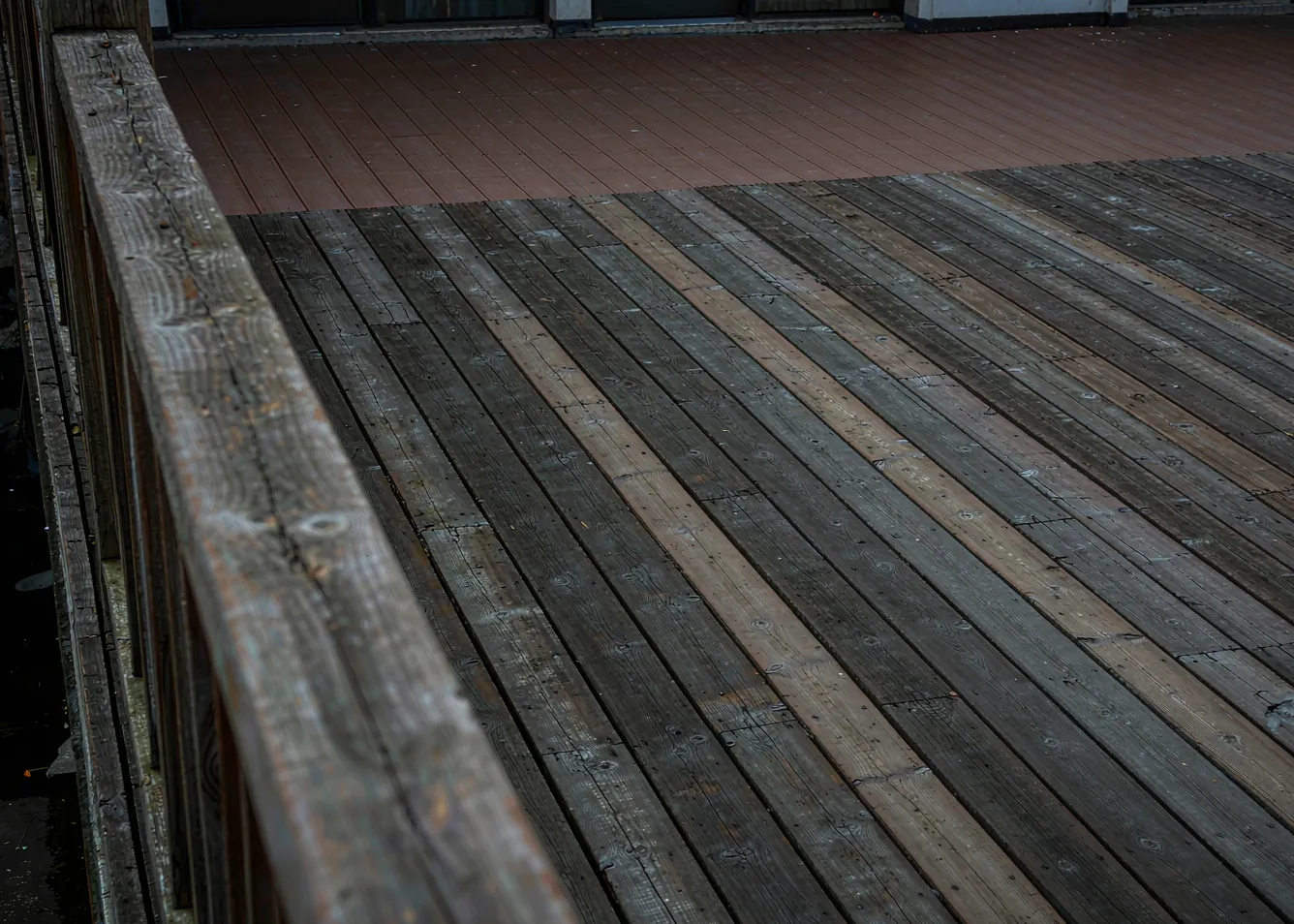 Weathered natural wood deck beside pristine composite deck showing maintenance difference