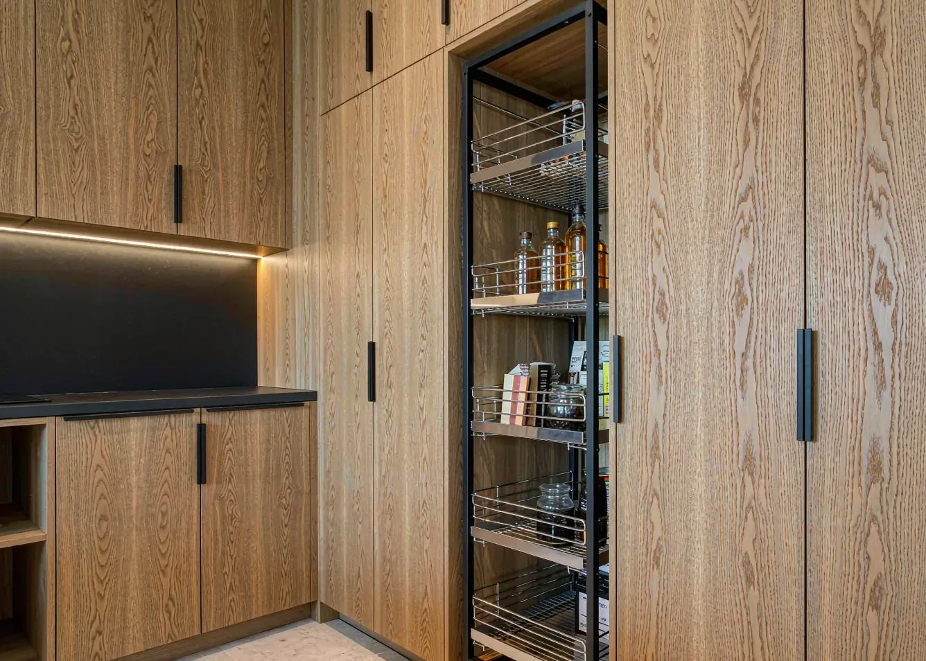Floor-to-ceiling oak cabinets with pull-out pantry storage in an open plan kitchen