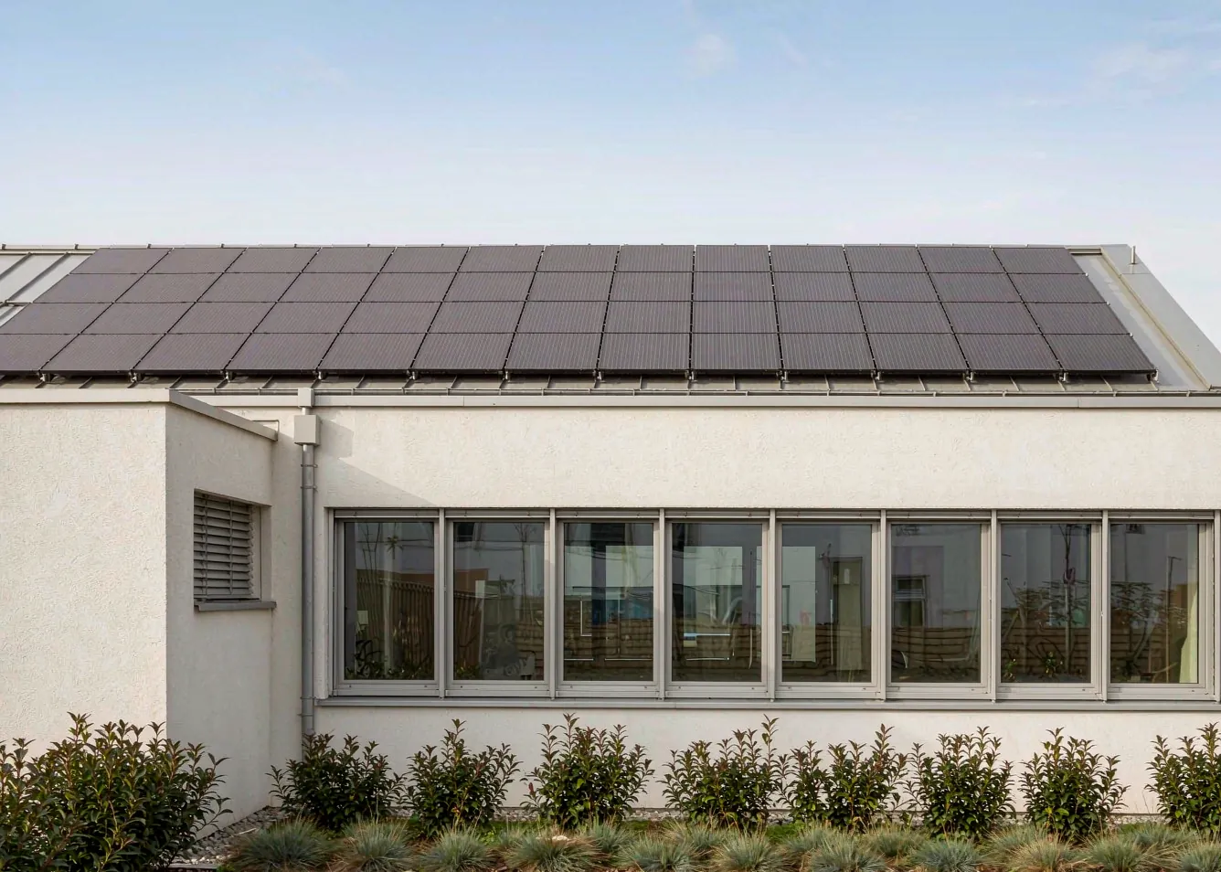 Modern house facade with aluminum windows and rooftop solar panels